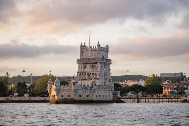 Tower of belem surrounded by the sea and buildings under a cloudy sky in portugal Free Photo