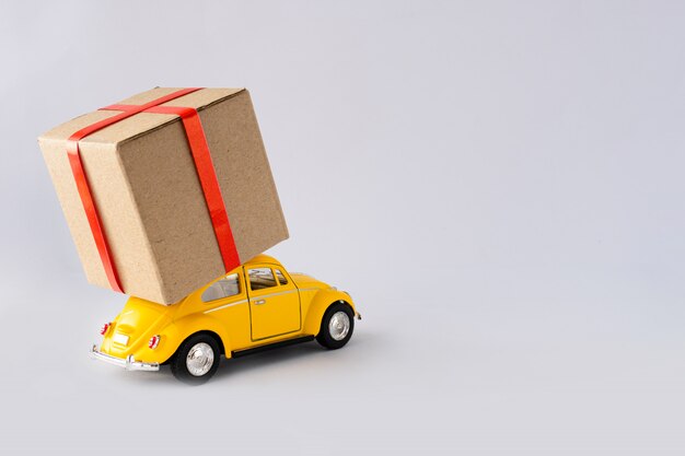 Premium Photo | Toy yellow car is carrying a parcel.