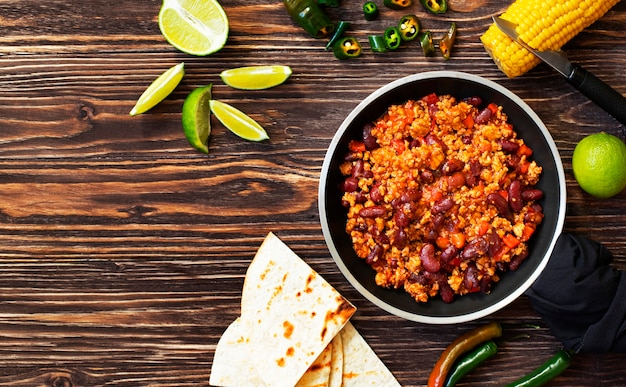 Premium Photo Traditional Mexican Chili Con Carne Served On A Rustic Wooden Table In A Pan With Corn Mexican Tortilla Bread Lime And Jalapeno Top View