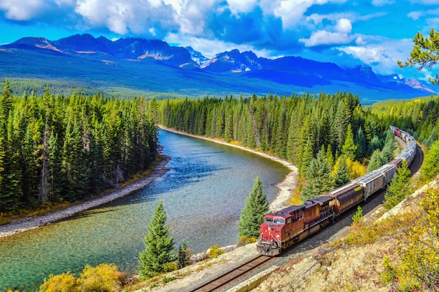 Premium Photo | Train passing famous morant's curve at bow valley in autumn