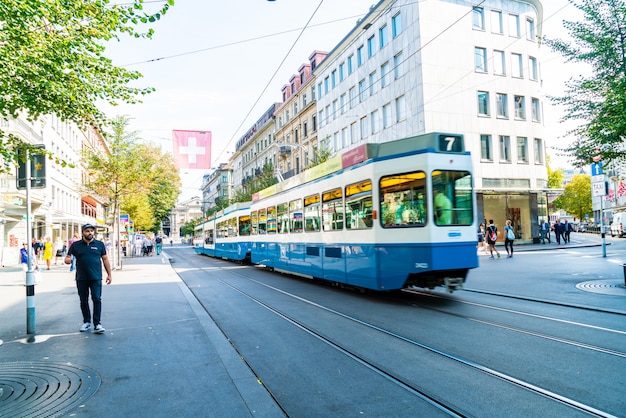 A tram drives down the center of bahnhofstrasse while people walk on the sidewalks in zurich, switzerland. Premium Photo
