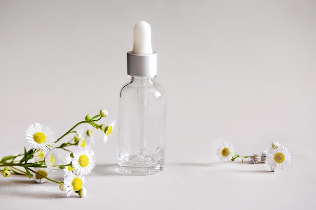 ピペットとカモミールハーブの花と化粧品のための透明なガラス血清化粧品ボトル プレミアム写真