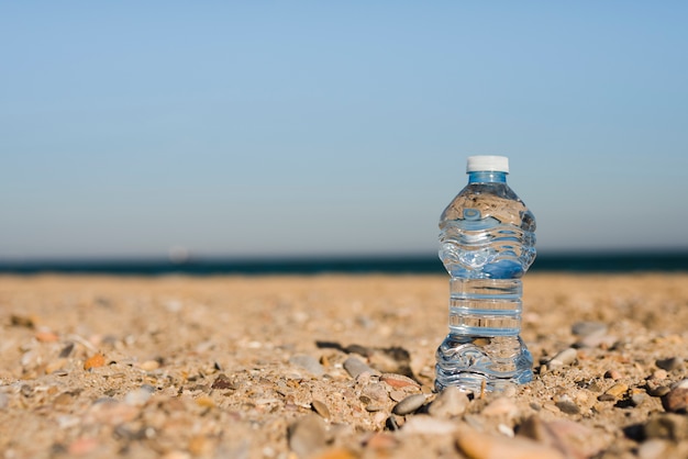 Transparent Plastic Water Bottle In Sand At Beach 