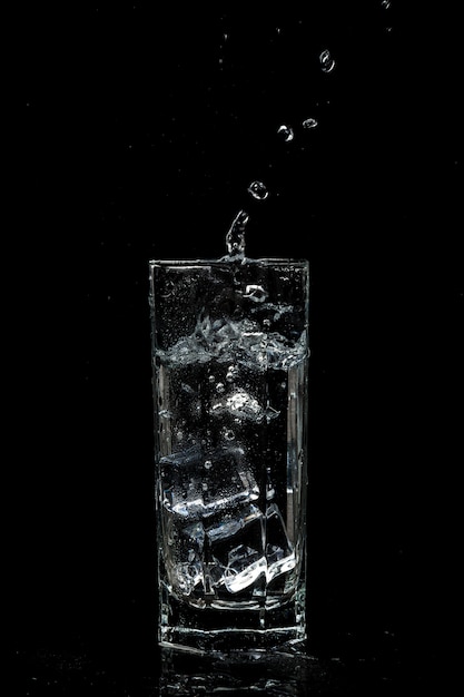 分離された黒のガラスの背景に氷で透明な水のガラス プレミアム写真