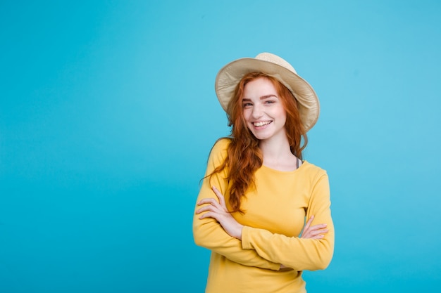 Travel concept - close up portrait young beautiful attractive redhair girl wtih trendy hat and sunglass smiling. blue pastel background. copy space. Free Photo
