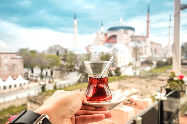 Travel woman with turkish tea looking view of hagia sophia in istanbul, turkey Premium Photo