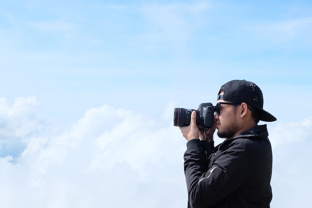 旅行者の男はカメラを保持して 美しい風景曇り背景の写真を撮る プレミアム写真