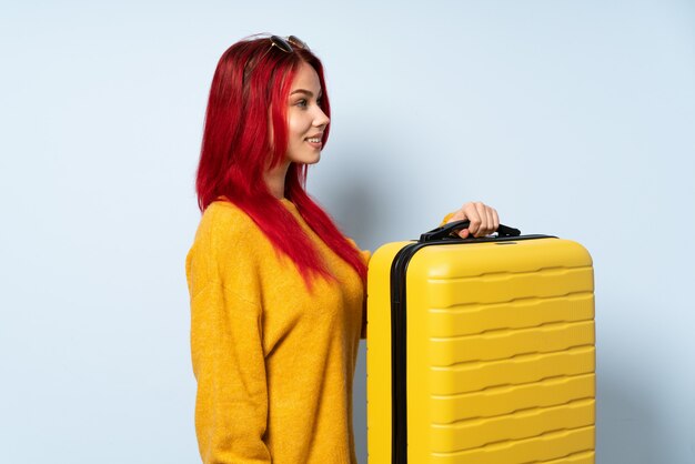 Premium Photo | Traveler woman holding a suitcase isolated on blue wall ...