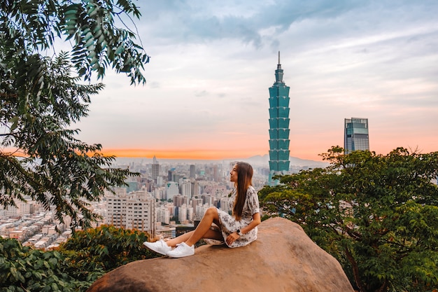 Traveler women and sunset with view of skyline of taipei cityscape taipei 101 building of taipei financial city ,taiwan Premium Photo