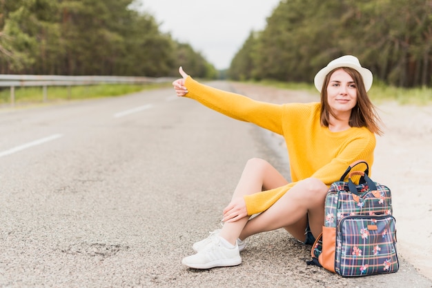 Traveling woman hitchhiking and sitting | Free Photo