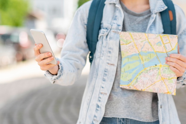 地図と携帯電話の正面図を持つ旅行者 プレミアム写真