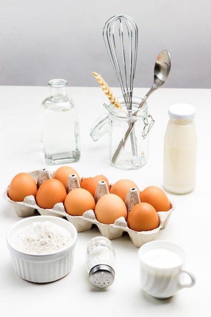 Premium Photo | Tray with brown eggs and bowl of flour. two bottles of ...