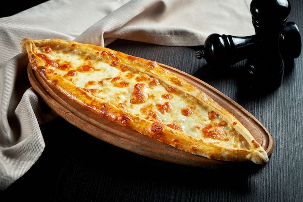 黒いテーブルにトマトと塩味のチーズを添えたトルコのピデ料理 | プレミアム写真