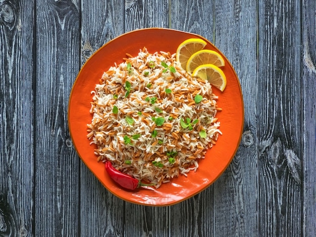 Turkish rice pilaf with orzo in a plate on a dark wooden background Premium Photo
