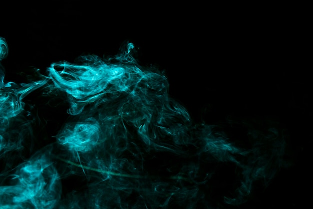 黒の背景にターコイズブルーの創造的な煙 無料の写真