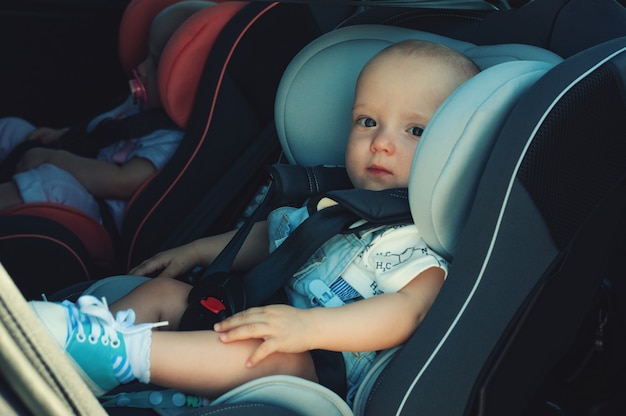 車のチャイルドシートの双子の男の子と女の子 赤ちゃんの安全輸送 1年までの子供 プレミアム写真