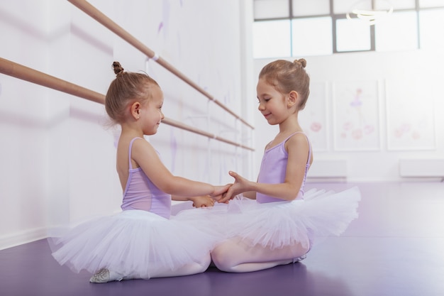 Romantik Uafhængighed hulkende Premium Photo | Two adorable little ballerinas holding hands smiling at  each other at ballet school. cute happy young ballet dancers resting after  practicing