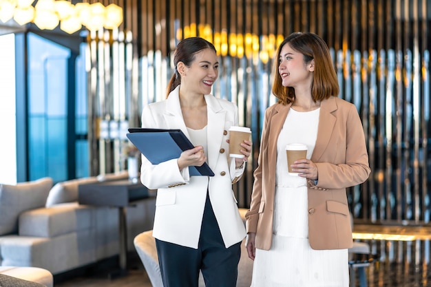 Two asian businesswomen talking during coffee break in modern ...