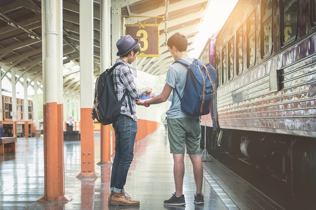 2つのバックパッカーと帽子が駅にあり 旅行の計画のための地図を見ている 旅行のコンセプト プレミアム写真