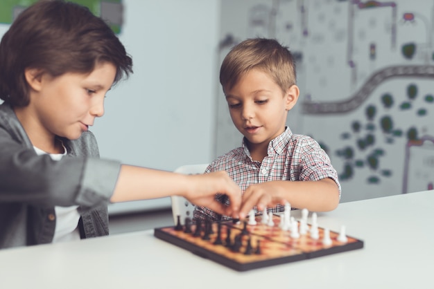 Premium Photo | Two boys play chess sitting at a table and are bored.