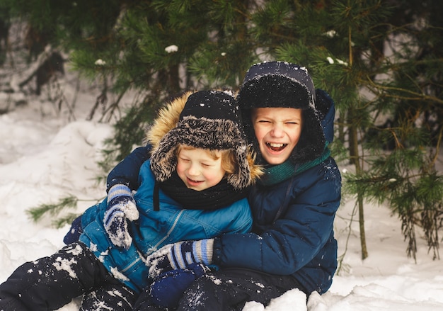 Premium Photo | Two boys play in the snow in a beautiful winter forest.