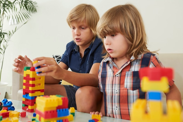 Premium Photo | Two brothers playing with plastic blocks