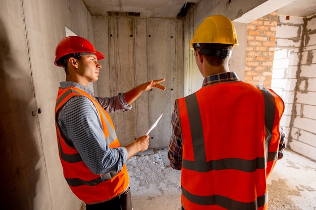 Premium Photo Two Civil Engineers Dressed In Orange Work Vests And