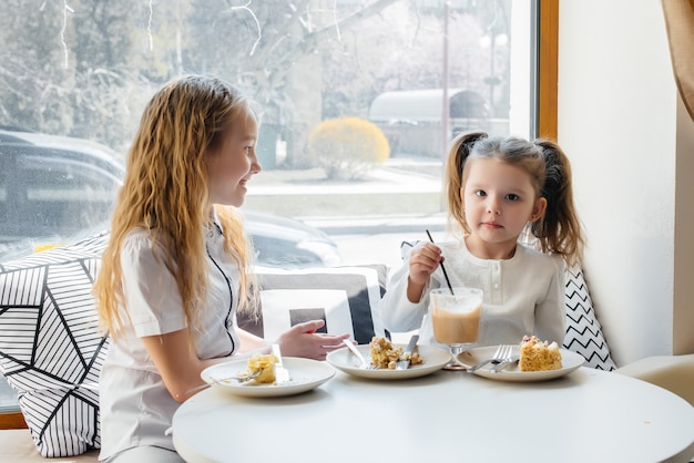 2人のかわいい女の子がカフェに座って 晴れた日に遊んでいます プレミアム写真