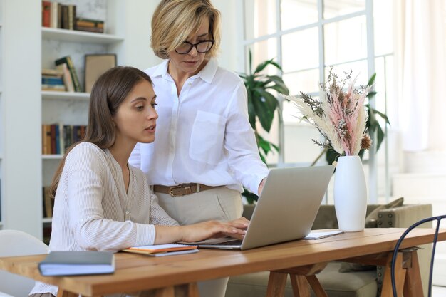 Premium Photo | Two female collegues working with laptop and discussing ...