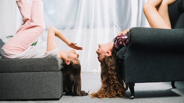 free-photo-two-female-friends-lying-upside-down-on-chair-opposite