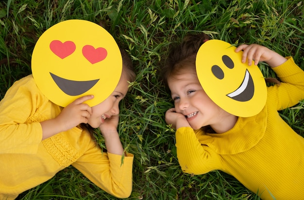 Premium Photo | Two funny little girls are lying on the lawn covering ...