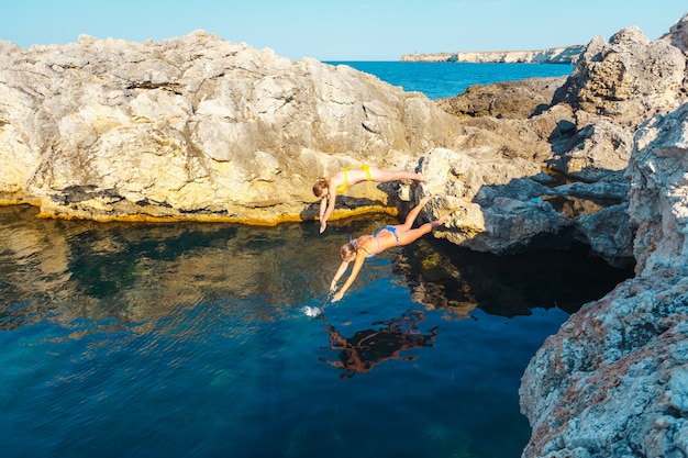 二人の少女が崖から海に飛び込む プレミアム写真
