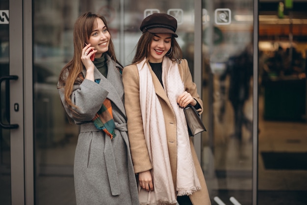 Premium Photo | Two girls outside shopping mall with phone in an autumn day