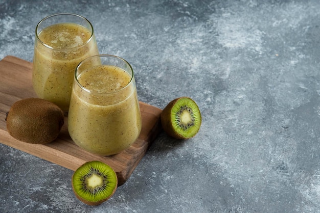 Free Photo | Two glass cups of tasty kiwi juice on wooden board.