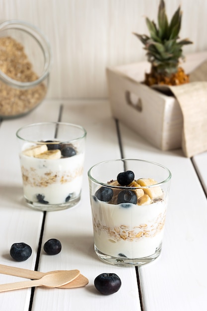 Premium Photo | Two glasses with layered yogurt oats and fruits on ...