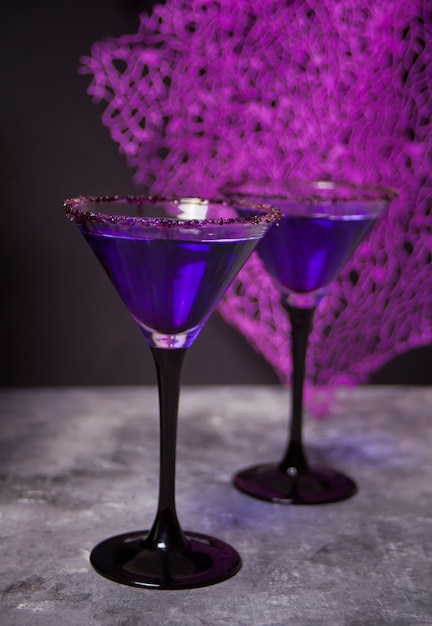 暗闇の中でハロウィーンパーティーのための紫色のカクテルと2つのメガネ プレミアム写真