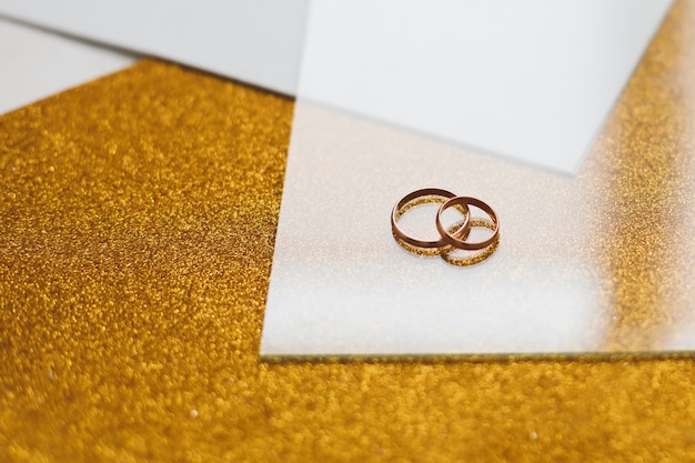 Premium Photo | Two golden wedding rings on a golden background.