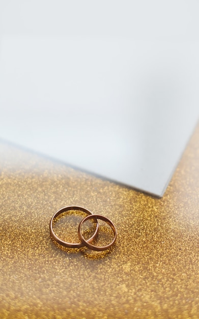 Premium Photo | Two golden wedding rings on a golden background.