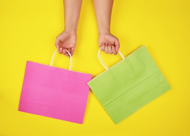 Download Two Hands Holding Paper Shopping Bags On A Yellow Background Premium Photo Yellowimages Mockups