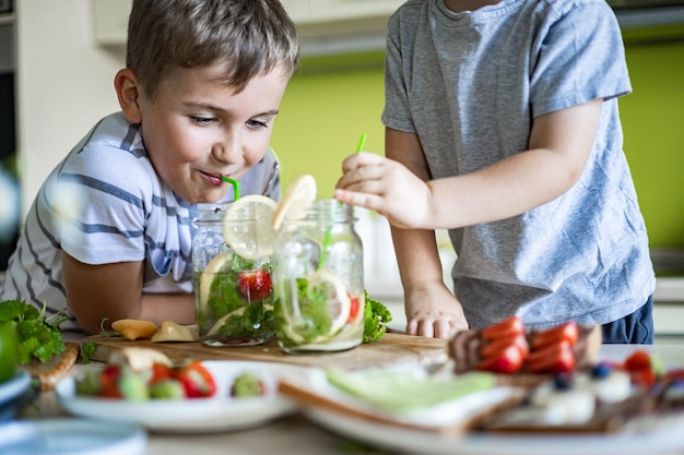 Premium Photo | Two laughing little boys drinking refreshing vitamin ...