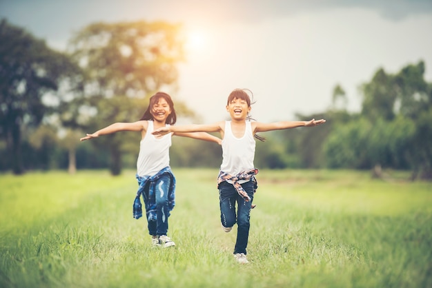 Two little cute girls are running on green grass. Best friends. Free Photo