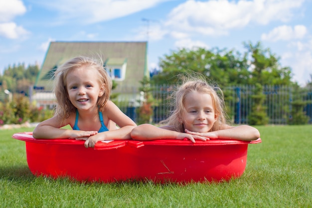 Premium Photo Two Little Sisters Frolicing And Splashing In Their Yard In Small Pool