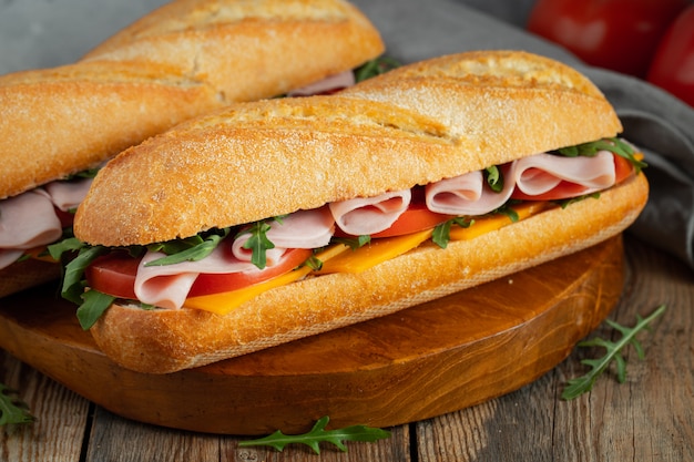 Premium Photo | Two long baguette sandwiches with ham and cheese.