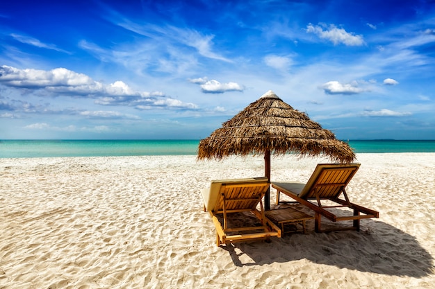 Premium Photo | Two lounge chairs under tent on beach