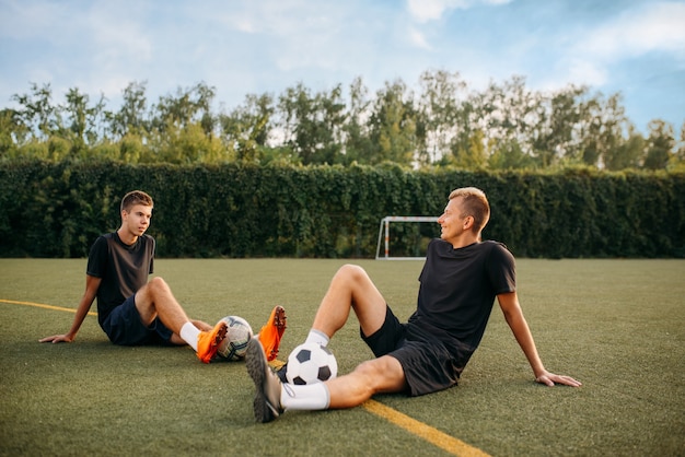 Premium Photo | Two male soccer players resting on the grass on the ...