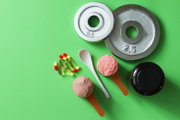 Two measuring spoons of whey protein and disks on table Premium Photo