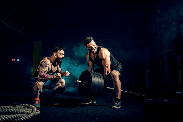 Premium Photo | Two muscular bearded tattooed athletes training, one ...