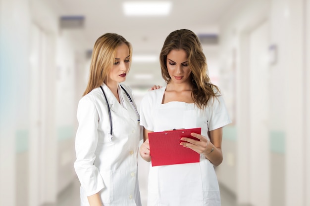 Free Photo Two Pretty Young Women Doctors Nurses Looking Through The