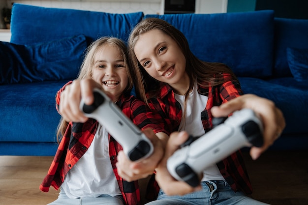 Premium Photo | Two sisters at home have fun and play a console with a ...