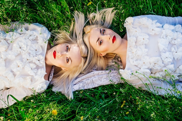 Premium Photo Two Sisters Twins Lying On Green Grass